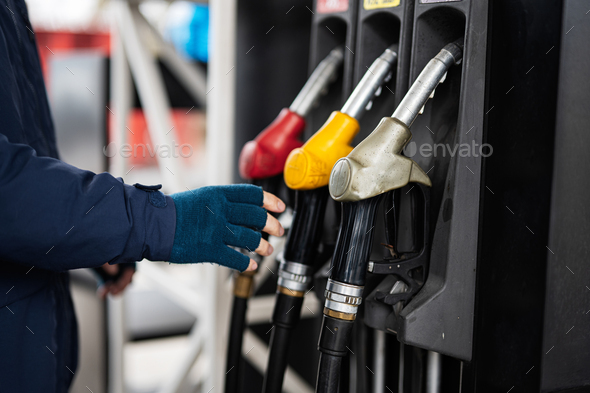 Close up hand of man hold fuel pump while refueling his car at the gas station in cold weather. - Stock Photo - Images