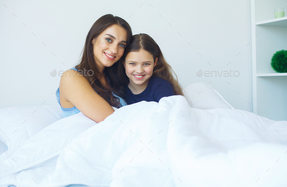 Woman and young girl lying in bed smiling Stock Photo by maksymiv ...