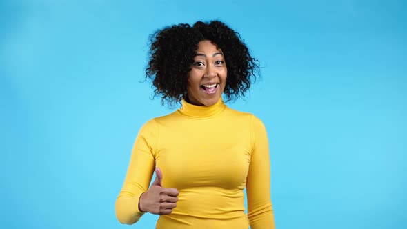 African Woman Showing Like Thumb Up Sign Over Blue Studio Background alt
