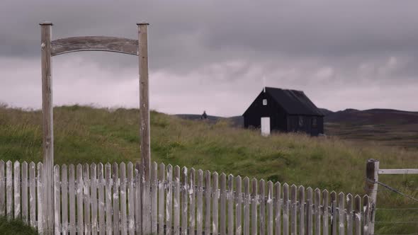 Stylish Man with a Sack Bag and Banjo Case Walks Towards Little Black House alt