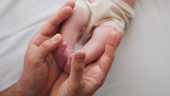 Father Holding Feet of Newborn Baby alt