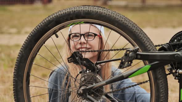 An Elevenyearold Girl Twists and Looks at the Wheel of Her Bicycle alt