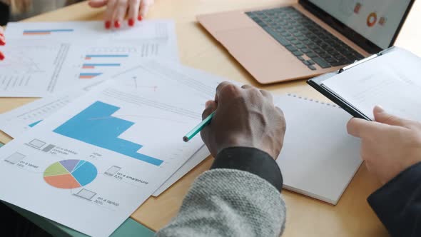 Group of Unrecognizable Business People Analyze Statistics Graphs and Diagrams