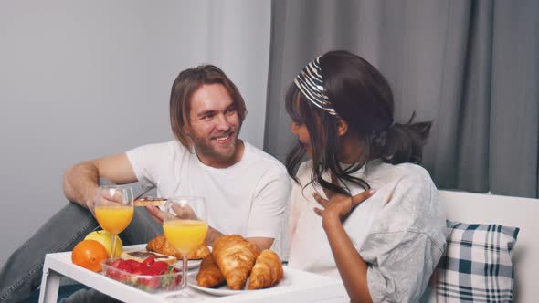 Young Multiracial Newlywed Couple Having Breakfast in the Bed on the Honeymoon alt