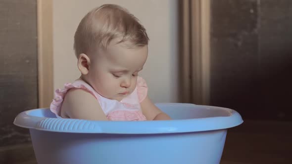 Cute Baby Girl in a Round Blue Tub alt