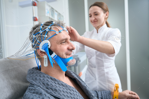 Doctor attaches the sensors to the patient head - Stock Photo - Images