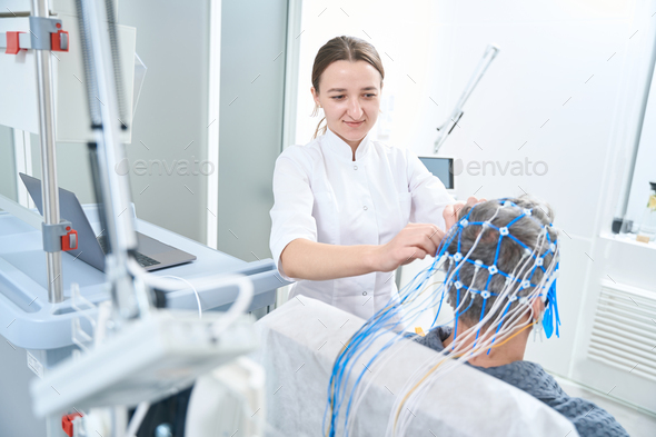 Woman diagnostician attaches sensors to the patient head - Stock Photo - Images