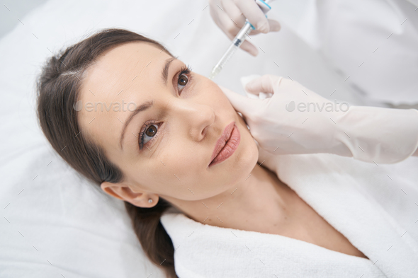 Doctor cosmetologist making beauty injection into client face