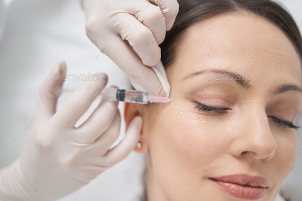 Doctor beautician doing contour plastic injection into woman face