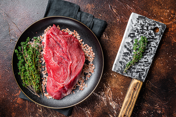 Raw beef sirloin steak with herbs and salt. Dark background. Top view