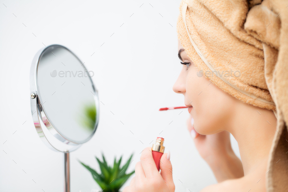 Pretty young woman puts makeup on the face in the bathroom