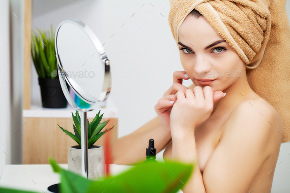 Pretty young woman puts makeup on the face in the bathroom