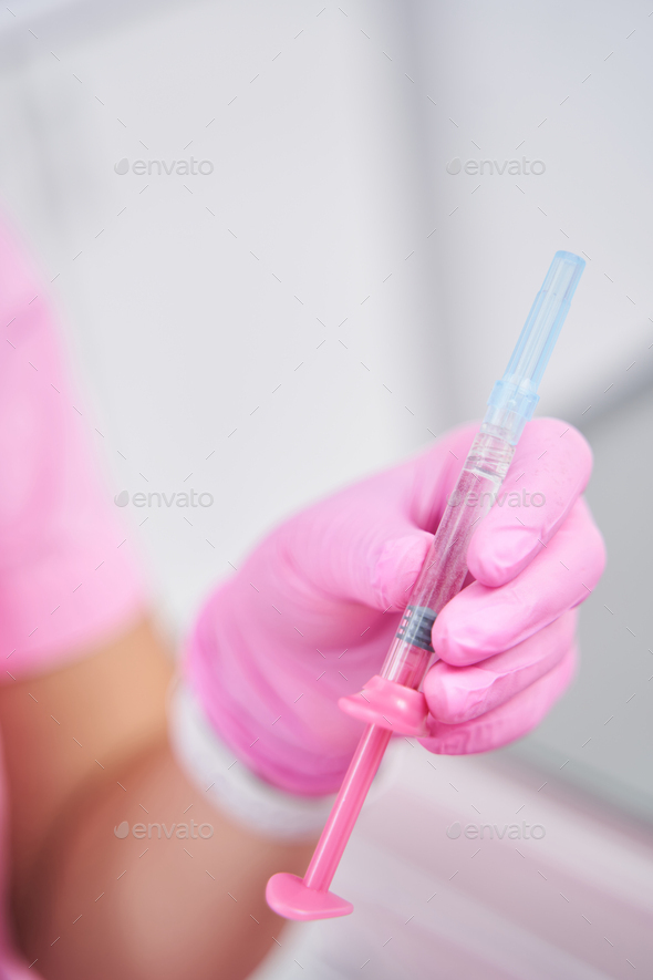 Female medical worker holds hypodermic syringe in her left hand Stock