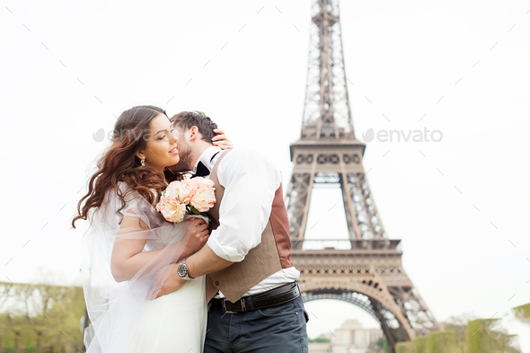 Just married couple near the Eiffel tower on their wedding day. Bride and groom in Paris, France