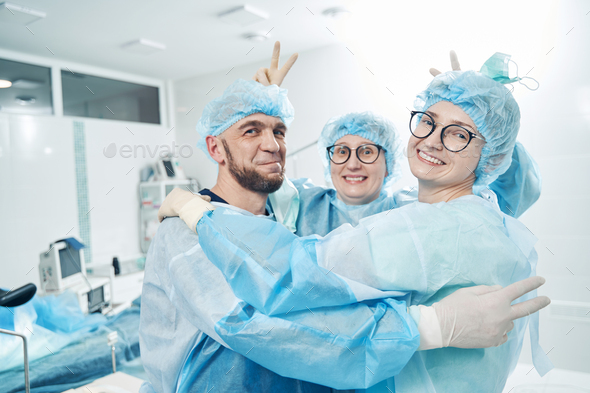 Nurse giving bunny ears to two colleagues in medical room