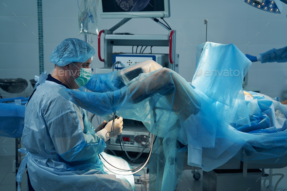 Male Gynecologist Performing Hysteroscopy Procedure In Clinic Stock