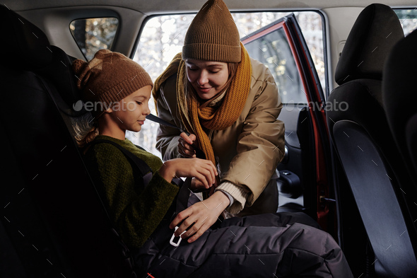 Mom fastening daughter with seat belts - Stock Photo - Images
