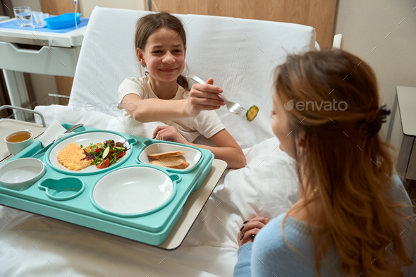 Young lady having lunch in clinic with mother - Stock Photo - Images