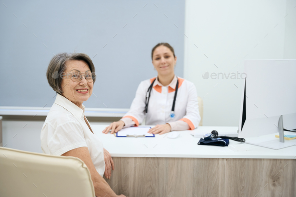 Two women in good mood are sitting in doctor office - Stock Photo - Images
