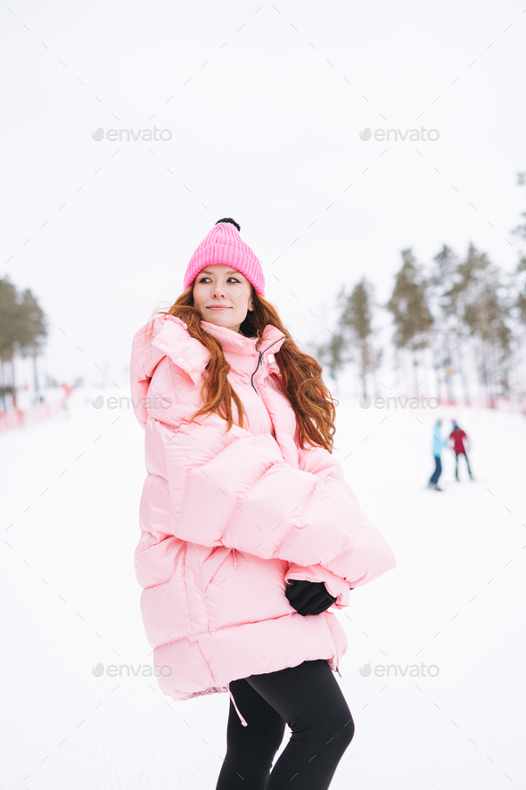 Young red haired woman in pink sportswear on winter snowy background - Stock Photo - Images