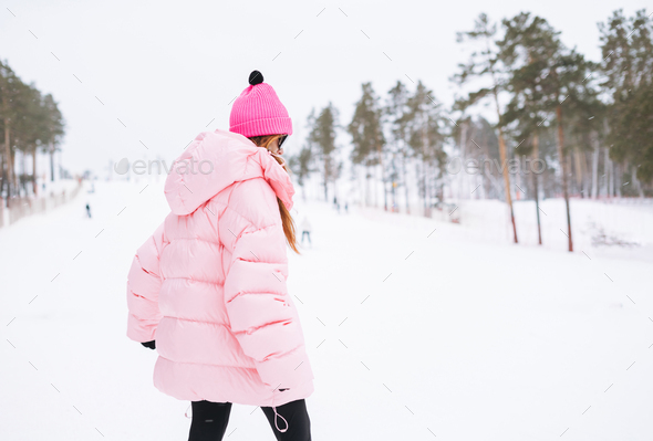Young red haired woman in pink sportswear and sunglasses on winter snowy background - Stock Photo - Images