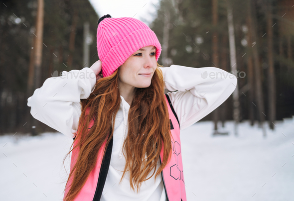 Young red haired woman in pink sportswear running in winter snowy forest - Stock Photo - Images
