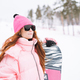 Young red haired woman in pink sportswear with snowboard on winter snowy background - PhotoDune Item for Sale