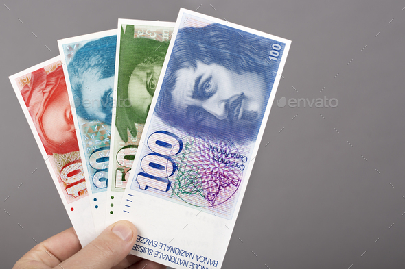 Old Swiss franc in the hand on a gray background - Stock Photo - Images