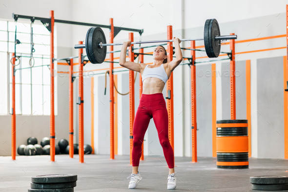 Strained sportswoman doing barbell push press - Stock Photo - Images