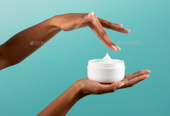 Anonymous black woman taking cream from jar - Stock Photo - Images