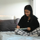 Cute teenager girl writing down in notebook, doing homework on bed at home.  - PhotoDune Item for Sale