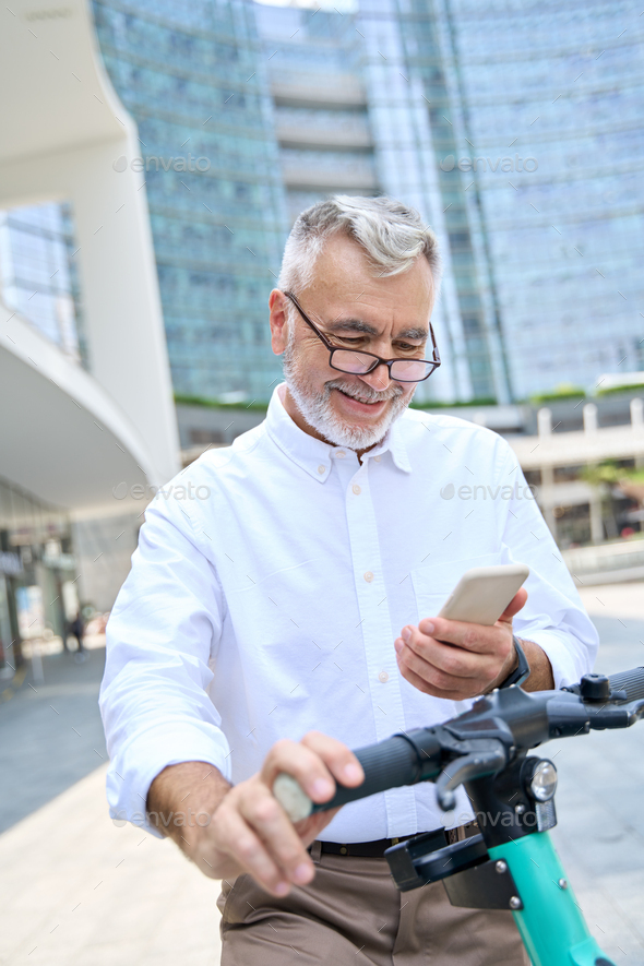 Happy older man using mobile app for bike rental renting bike in city park. - Stock Photo - Images