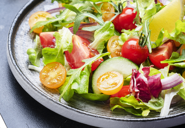 Fresh spring vegan vegetables salad with colorful cherry tomatoes, cucumber, red onion - Stock Photo - Images