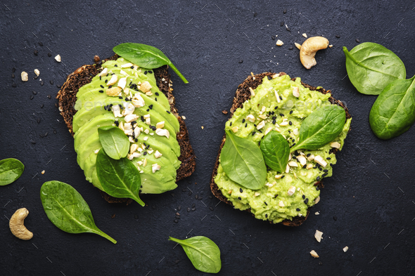 Avocado sandwich or toast on rye bread with spinach, crushed cashew nuts  - Stock Photo - Images