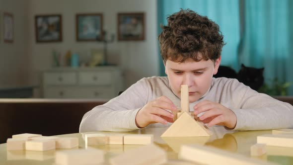 Caucasian preschool child plays with game cubes at a table in the living room. alt