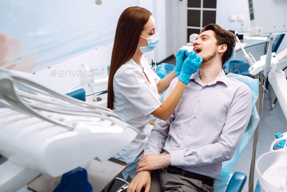 Young man at the dentist's chair during a dental procedure. Overview of ...