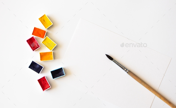Colorful watercolor pallets, paper sheet and paintbrush on white background