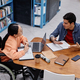 Asian teenage girl with disability talking to friend in college library - PhotoDune Item for Sale