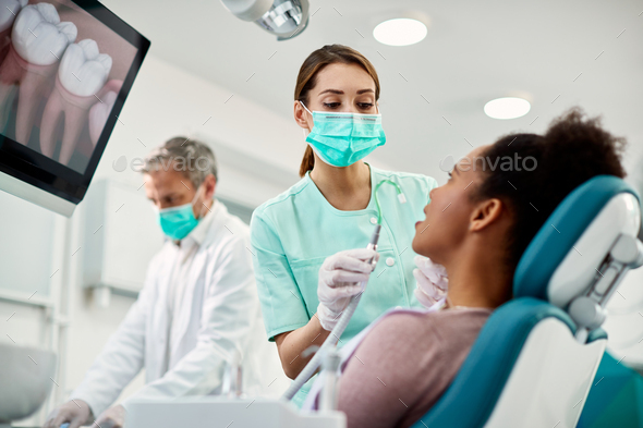 Young nurse preparing patient for dental procedure at dentist\'s office.