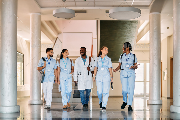 Multi-ethnic group of happy medical students walking through hallway at medical university.