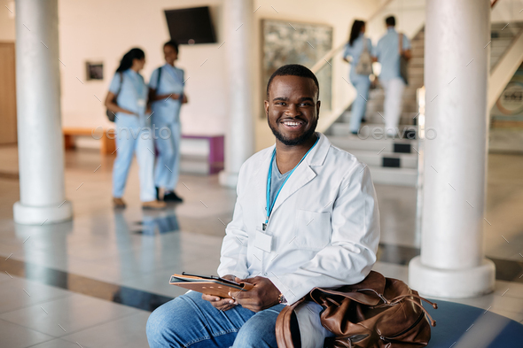 Happy black medical student at university hallway looking at camera.