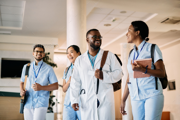 Group of happy medical students talking while walking through hallway at the university.