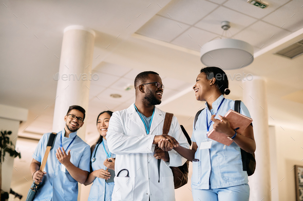 Below view of happy African American medicals students greeting in a hallway at the university.
