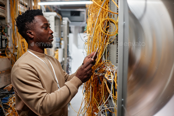 System administrator setting up server and using smartphone - Stock Photo - Images