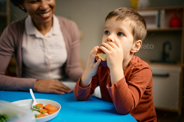 Little boy having an apple for a snack at kindergarten. - Stock Photo - Images