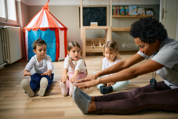 Group of kids and their teacher stretching during exercise class at preschool. - Stock Photo - Images