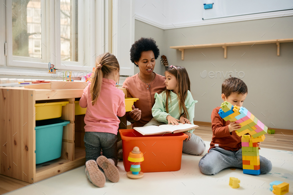African American teacher playing with group of children at preschool. - Stock Photo - Images