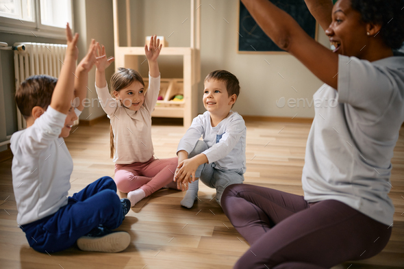 Happy children having fun with their teacher during exercise class at kindergarten. - Stock Photo - Images
