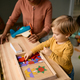 Small boy playing with wooden puzzle shapes with his teacher at kindergarten. - PhotoDune Item for Sale