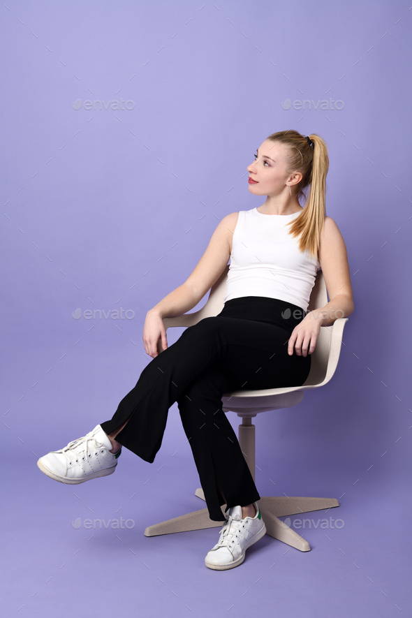 Beautiful blond woman sitting in a chair - Stock Photo - Images